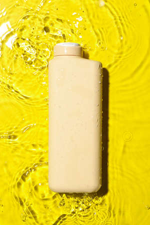 Bottle of shower gel into water on color backgroundの写真素材