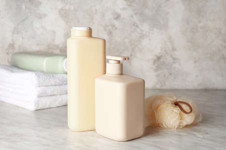 Bottles of shower gel, sponge and towels on light background