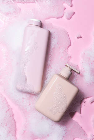 Bottles of shower gel into water with foam on color backgroundの写真素材