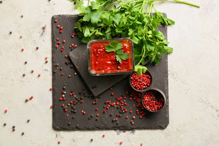 Bowl with sauce, parsley and peppercorns on light backgroundの写真素材