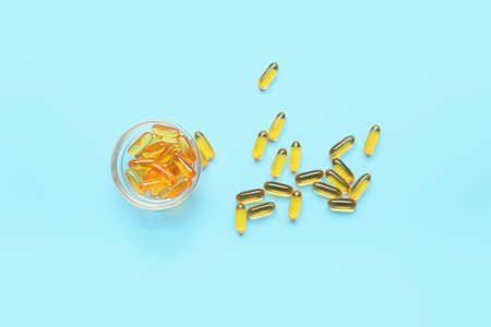 Bowl with fish oil capsules on color backgroundの写真素材