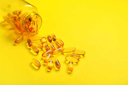 Bottle with fish oil capsules on color backgroundの写真素材