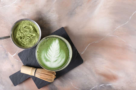 Glass of tasty matcha coffee with powder on grunge background with space for textの写真素材
