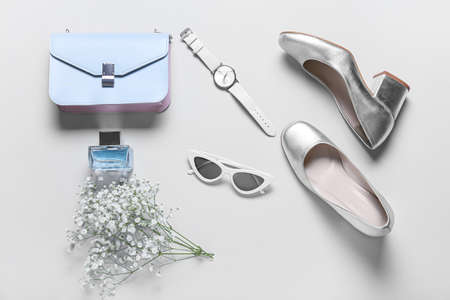 Stylish female accessories with flowers on gray background