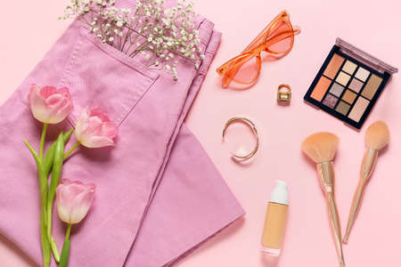 Stylish female accessories with clothes and flowers on color backgroundの写真素材