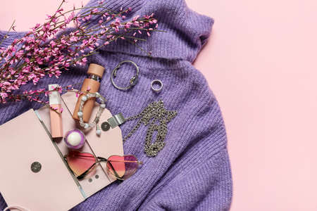 Stylish female accessories with clothes and flowers on color background