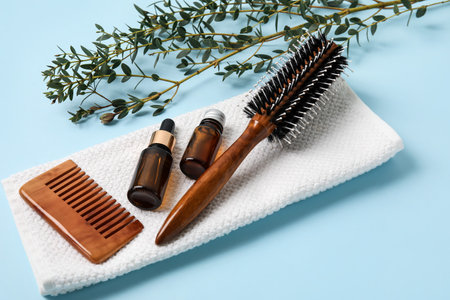 Hair brush, comb, towel and bottles of essential oil on color backgroundの写真素材