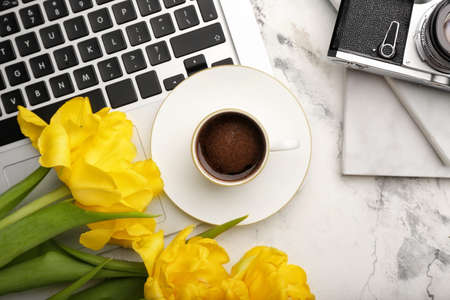 Cup of coffee with flowers, laptop and photo camera on white backgroundの写真素材