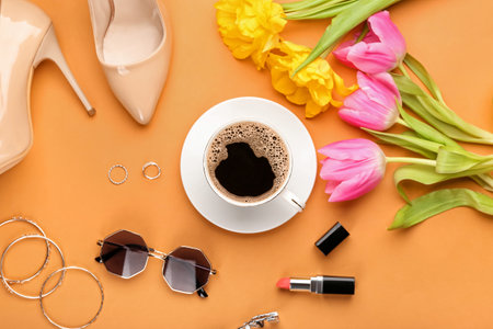 Cup of coffee with flowers and female accessories on color backgroundの写真素材