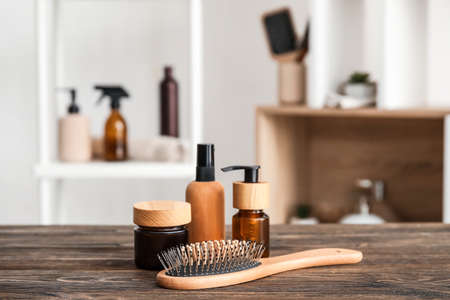 Hair brush and bottles of cosmetic products on wooden table in roomの写真素材