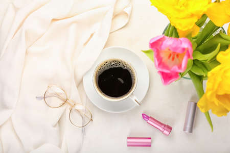 Cup of coffee with flowers and female accessories on white backgroundの写真素材