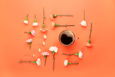 Cup of coffee with spring flowers on color background
