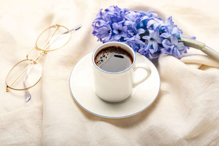 Cup of coffee with spring flowers and eyeglasses on clothの写真素材