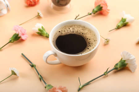 Cup of coffee with spring flowers on color backgroundの写真素材