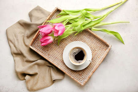 Tray with cup of coffee and flowers on light backgroundの写真素材