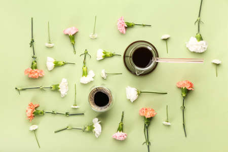 Tasty coffee with spring flowers on color background