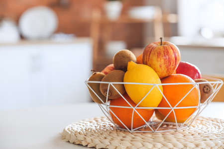 Basket with tropical fruits on table in kitchenの写真素材