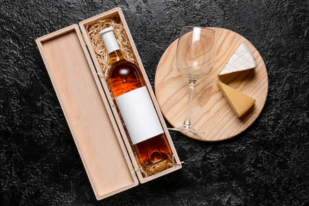 Box with bottle of wine, cheese and glass on dark backgroundの写真素材