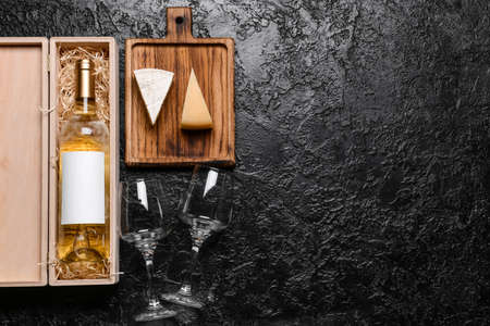 Box with bottle of wine, cheese and glasses on dark backgroundの写真素材