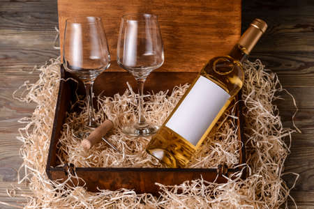 Box with bottle of wine and glasses on wooden backgroundの写真素材