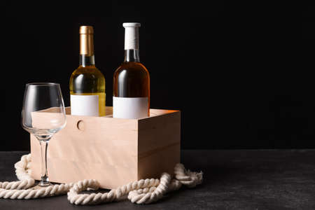 Box with bottles of wine and glass on dark backgroundの写真素材