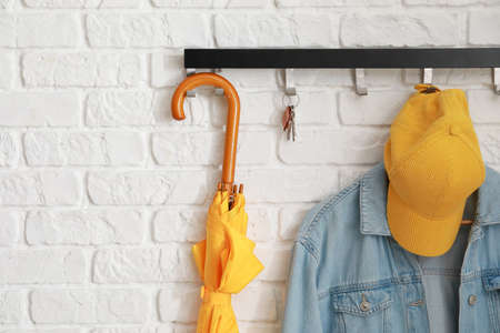 Rack with clothes and accessories hanging on brick wall