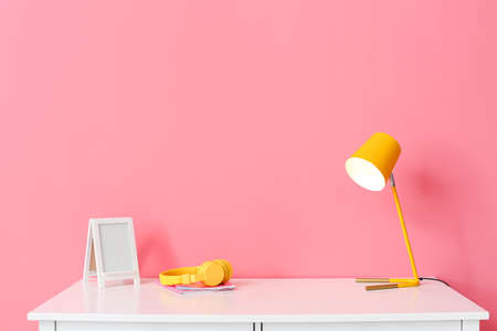 Modern lamp and headphones on table near color wallの写真素材