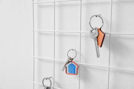 Holder with keys hanging on light wall, closeup