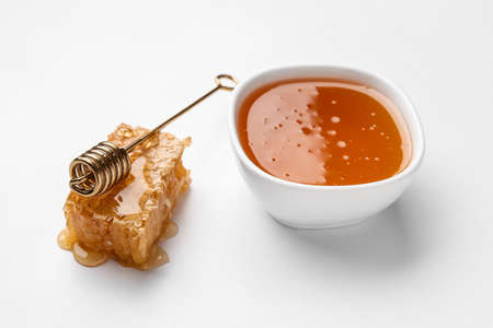 Bowl with sweet honey, dipper and comb on white backgroundの写真素材