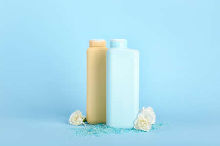 Shower gels and flowers on color background