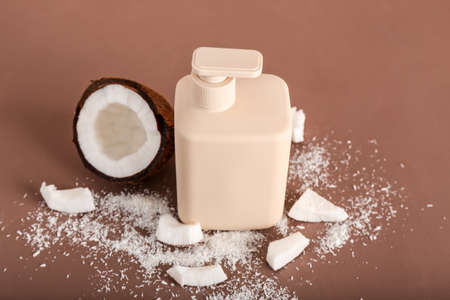 Shower gel and coconut on color background