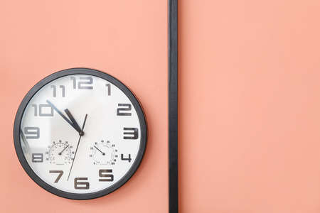 Stylish clock hanging on color wall