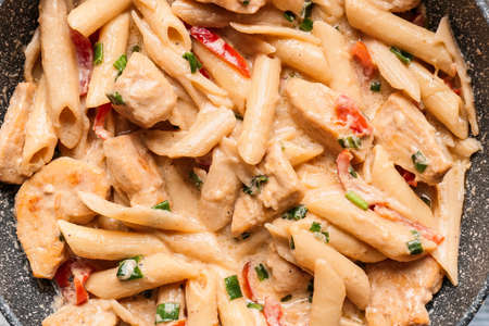 Frying pan with tasty cajun chicken pasta, closeup