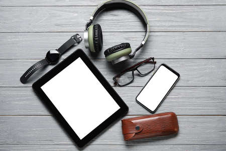 Different modern devices and eyeglasses on gray wooden background