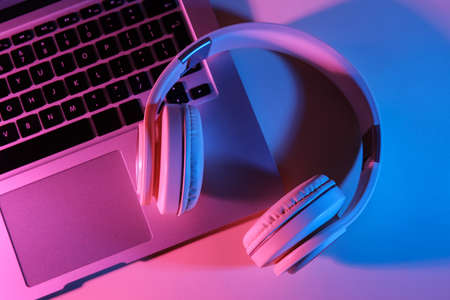 Modern laptop and headphones on color background, closeup