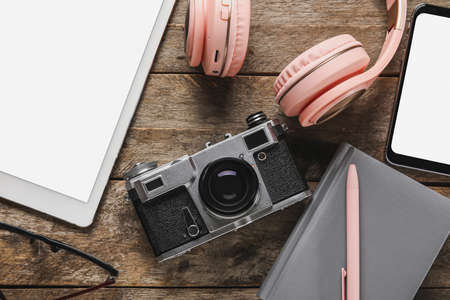 Different modern devices and notebook on wooden background