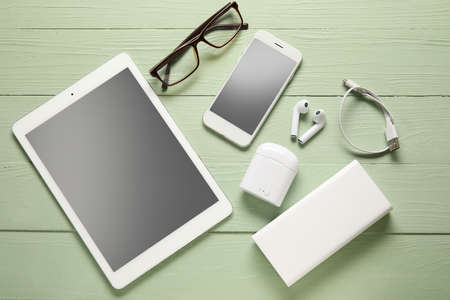 Different modern devices and eyeglasses on color wooden backgroundの写真素材