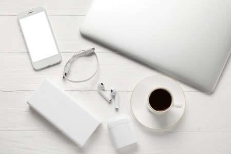 Different modern devices and cup of coffee on light wooden background