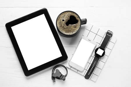 Different modern devices and cup of coffee on light wooden background