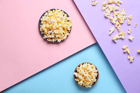 Bowls with tasty popcorn on color background