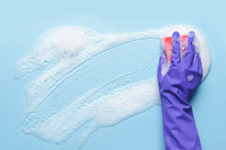 Woman with sponge cleaning color surface