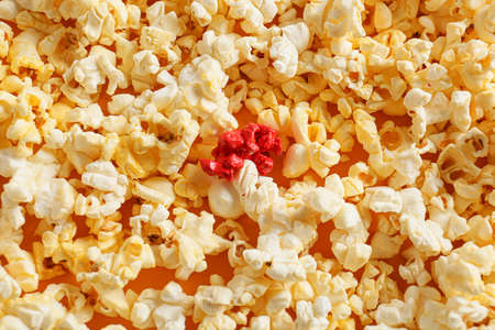 Pink popcorn among white ones on color background. Concept of uniquenessの写真素材