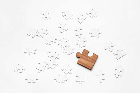 Wooden puzzle piece among blank ones on white background. Concept of uniquenessの写真素材