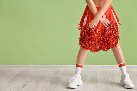 Beautiful cheerleader near color wall