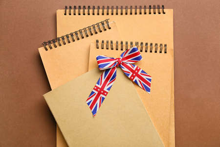 Notebooks and ribbon in colors of UK flag on color background. Concept of learning Englishの写真素材