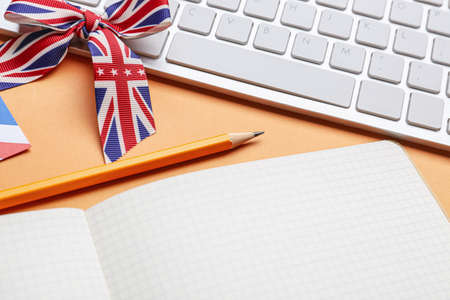 Stationery, keyboard and ribbon in colors of UK flag on orange background. Concept of learning Englishの写真素材