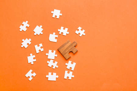 Wooden puzzle piece among white ones on color background. Concept of uniquenessの写真素材