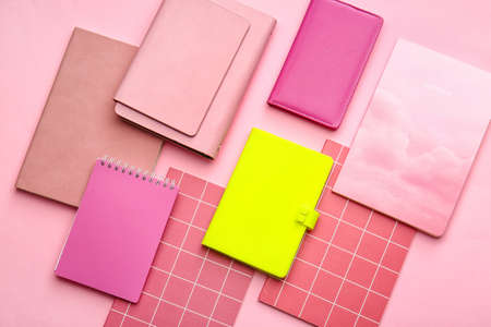 Yellow notebook among pink ones on color background. Concept of uniqueness