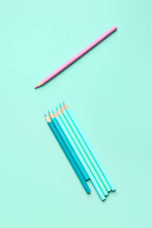 Pink pencil among blue ones on color background. Concept of uniquenessの写真素材
