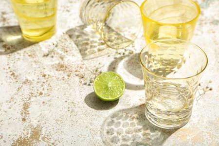 Beautiful glasses, flowers and lime on light background, closeupの写真素材